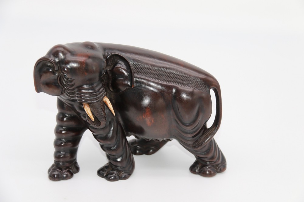 A pair of hand-carved dark hardwood elephant figures standing on pierced wooden bases with exposed tusks. View XXIV