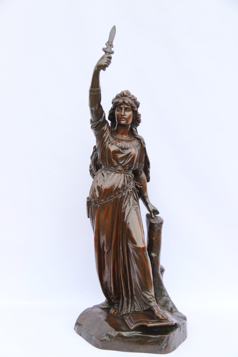 A 19th-century dark patinated bronze sculpture depicting Queen Boadicea in draped robes raising a dagger in her right hand while standing on a rocky base.