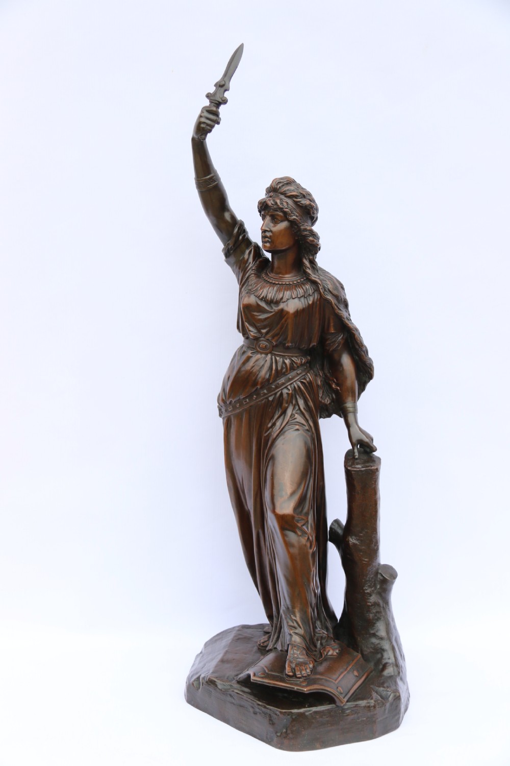A 19th-century dark patinated bronze sculpture depicting Queen Boadicea in draped robes raising a dagger in her right hand while standing on a rocky base. View II