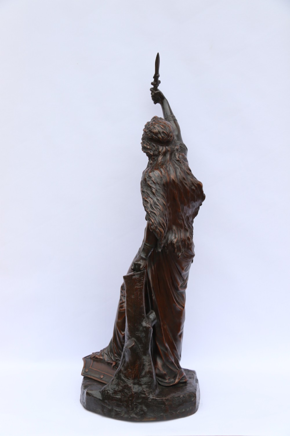 A 19th-century dark patinated bronze sculpture depicting Queen Boadicea in draped robes raising a dagger in her right hand while standing on a rocky base. View IV