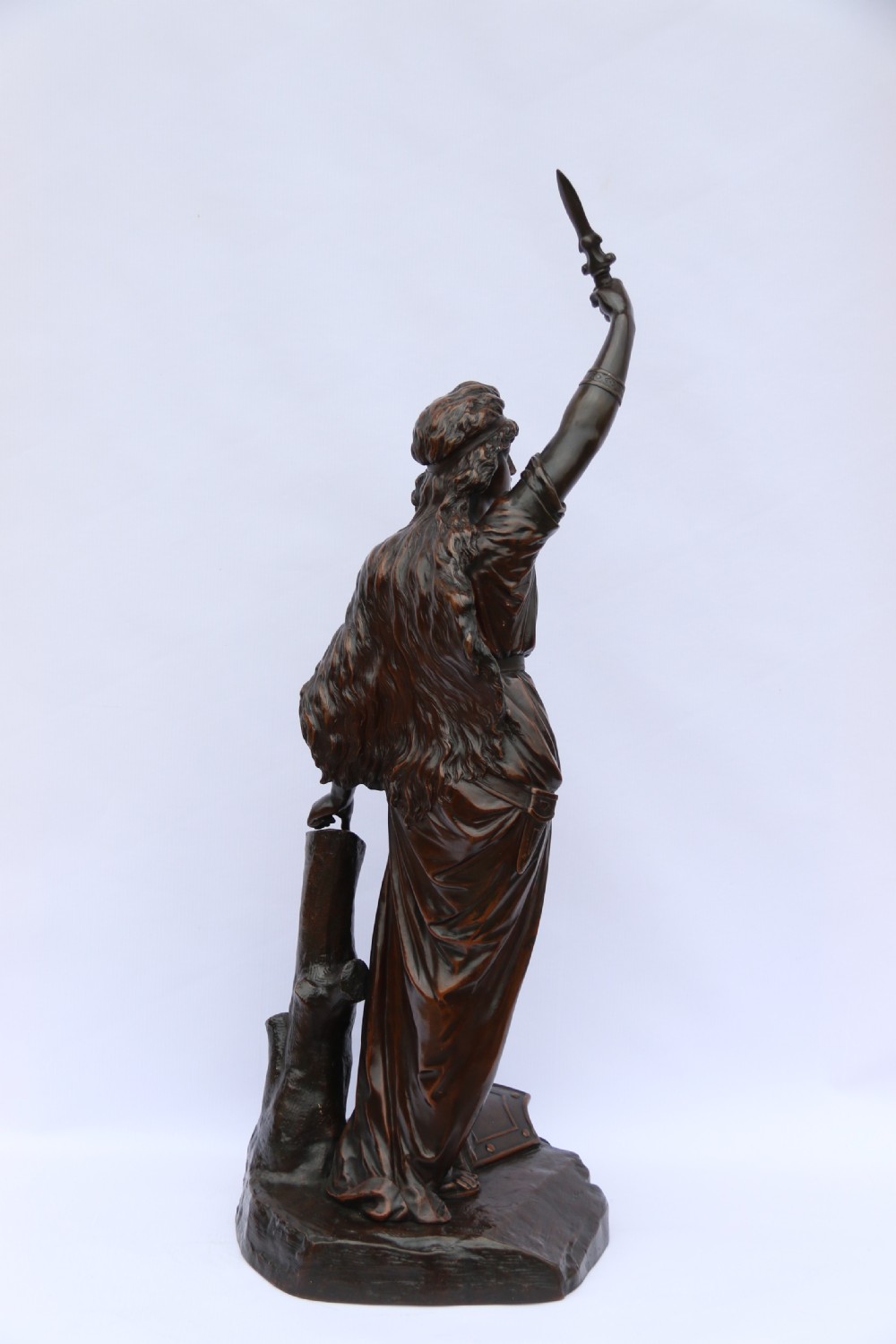 A 19th-century dark patinated bronze sculpture depicting Queen Boadicea in draped robes raising a dagger in her right hand while standing on a rocky base. View IX