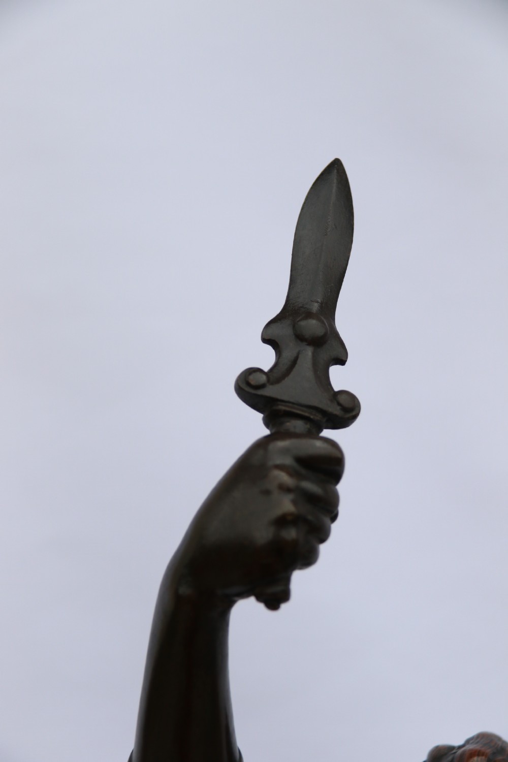 A 19th-century dark patinated bronze sculpture depicting Queen Boadicea in draped robes raising a dagger in her right hand while standing on a rocky base. View XIV
