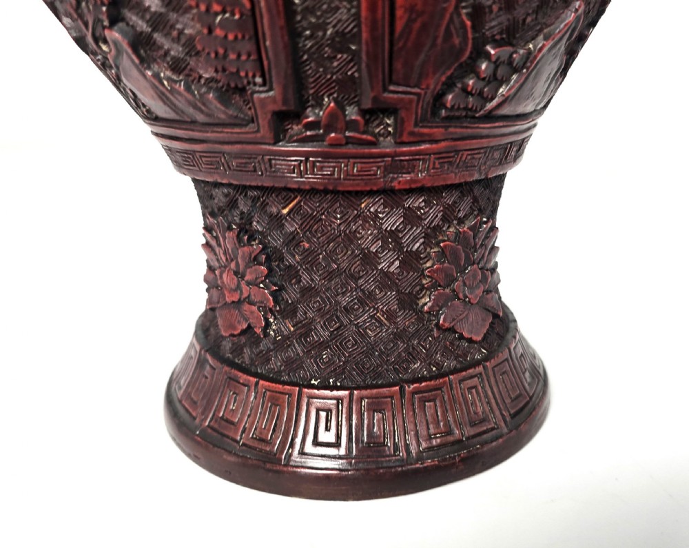 A baluster-shaped red cinnabar lacquer vase decorated with relief carvings of figures in a landscape surrounded by floral and geometric borders. View XV