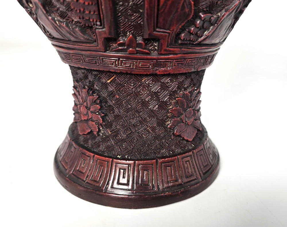 A baluster-shaped red cinnabar lacquer vase decorated with relief carvings of figures in a landscape surrounded by floral and geometric borders. View XVI