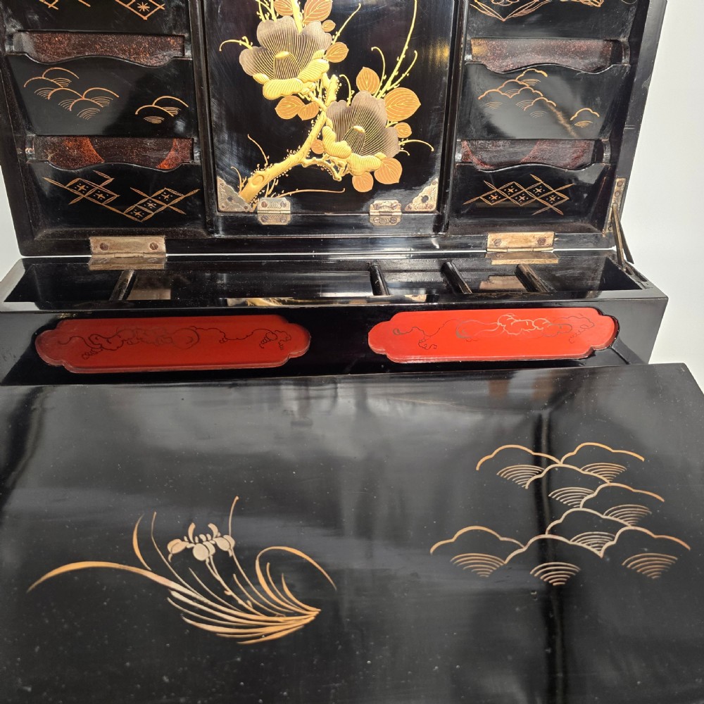 A black lacquer Japanese writing box decorated with detailed gold botanical and bird illustrations, featuring a hinged lid opening to internal correspondence slots. View XX