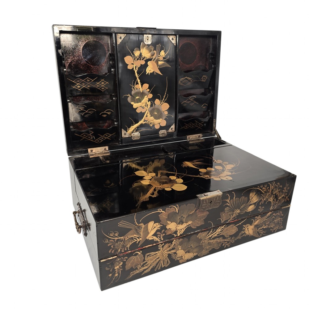 A black lacquer Japanese writing box decorated with detailed gold botanical and bird illustrations, featuring a hinged lid opening to internal correspondence slots.