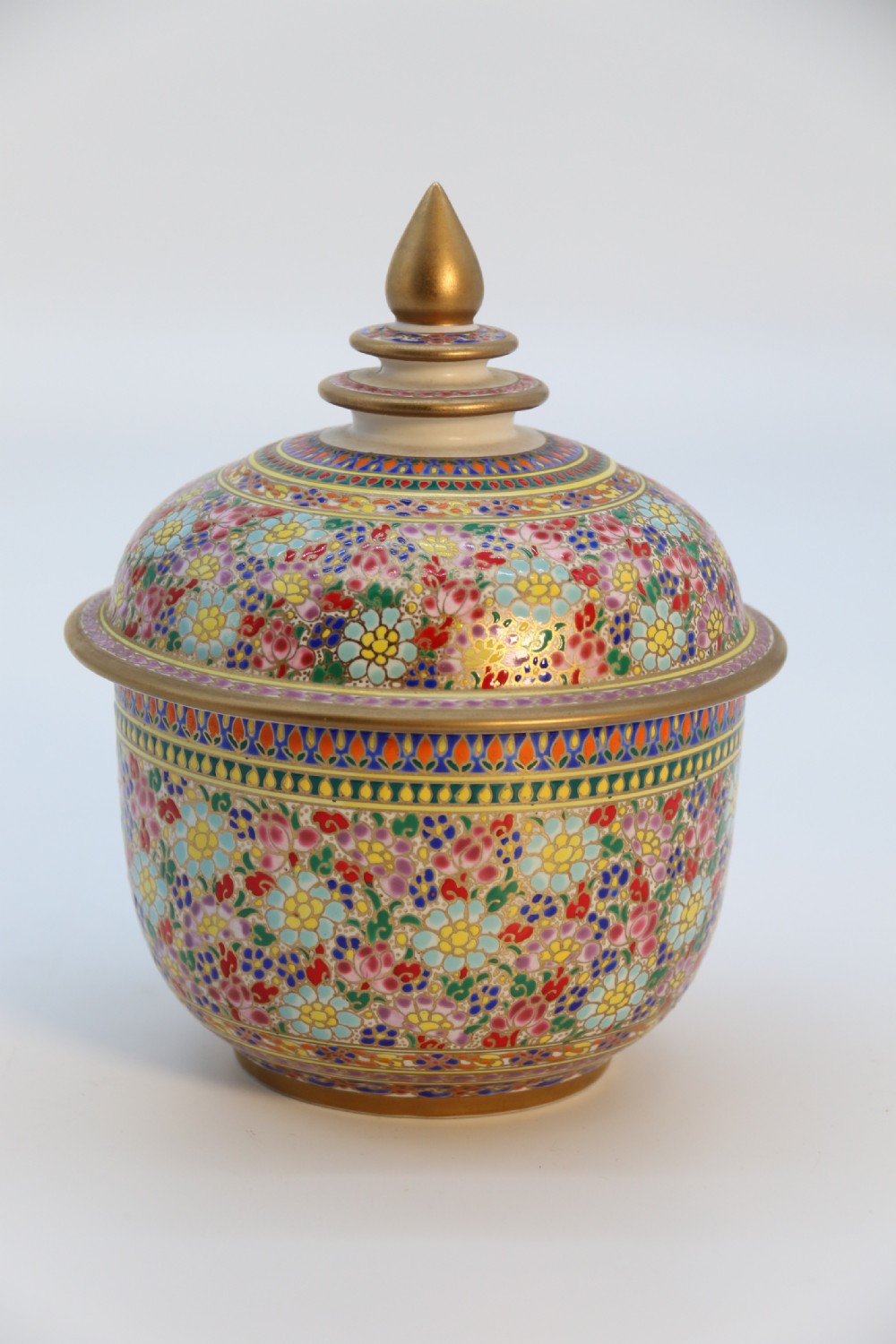 A polychrome enamelled ceramic jar with a fitted stepped lid featuring intricate floral motifs and a gilded conical finial. View III