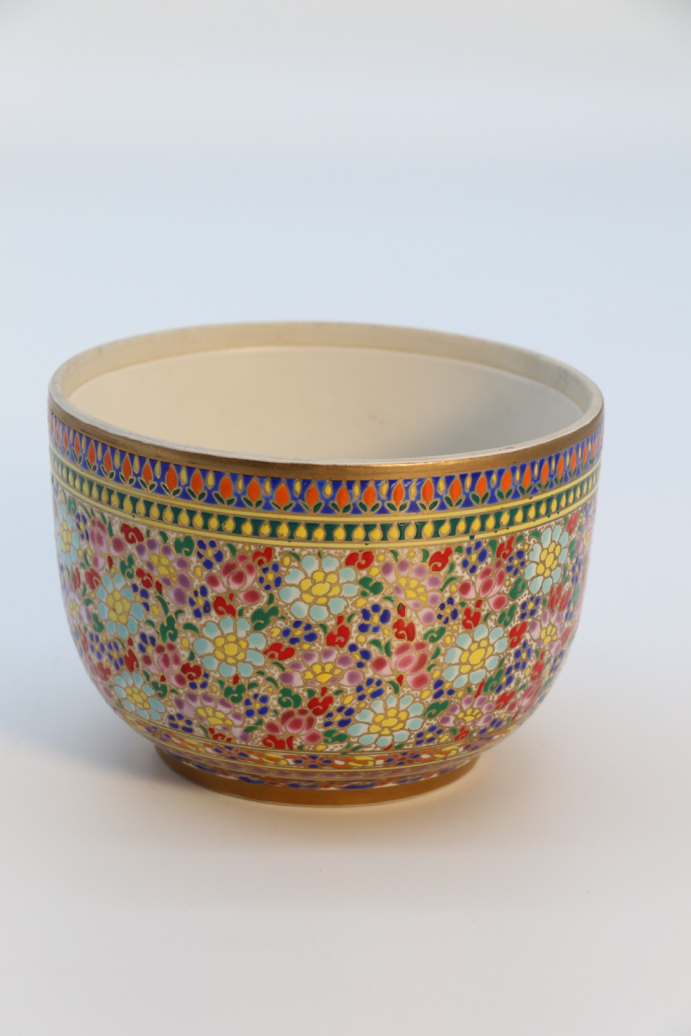A polychrome enamelled ceramic jar with a fitted stepped lid featuring intricate floral motifs and a gilded conical finial. View X