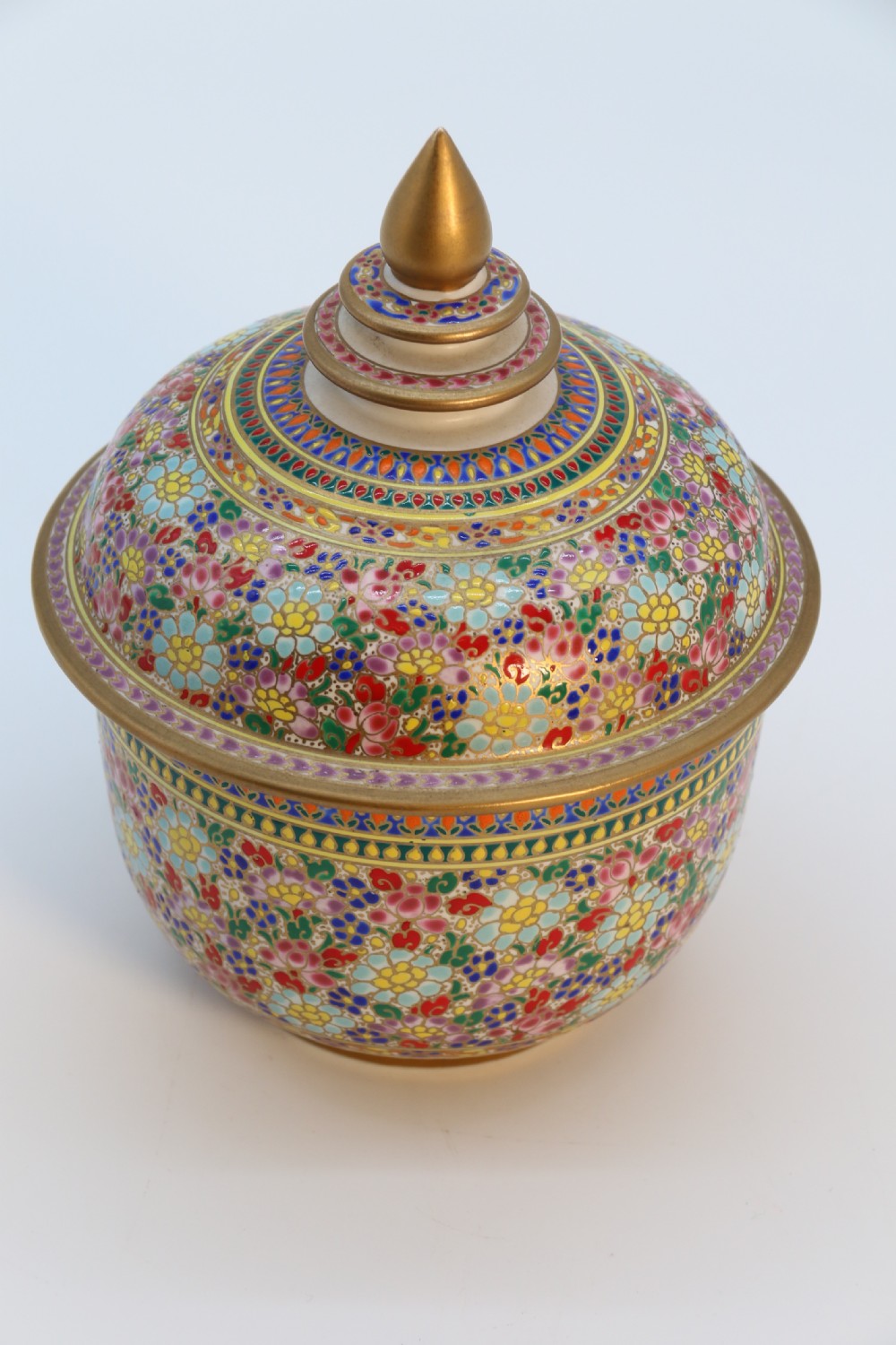 A polychrome enamelled ceramic jar with a fitted stepped lid featuring intricate floral motifs and a gilded conical finial. View XII