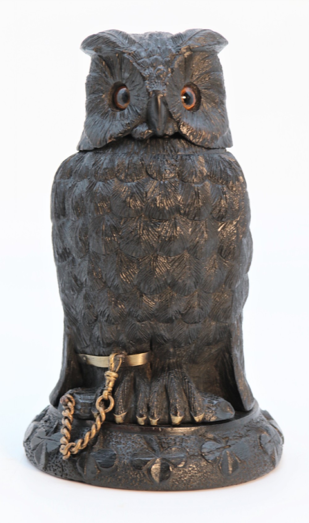A hand-carved dark oak inkstand crafted in the likeness of an owl with glass eyes and a brass tether, resting on a carved base with shamrock details.