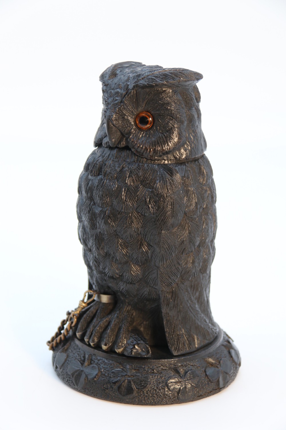 A hand-carved dark oak inkstand crafted in the likeness of an owl with glass eyes and a brass tether, resting on a carved base with shamrock details. View X