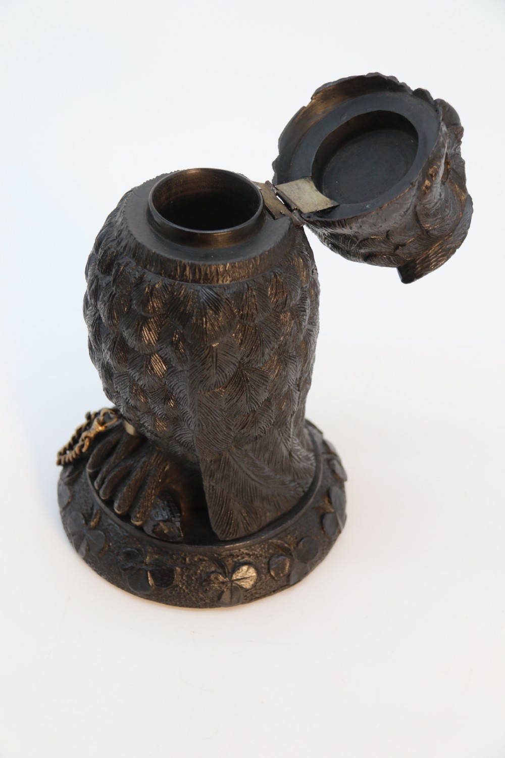 A hand-carved dark oak inkstand crafted in the likeness of an owl with glass eyes and a brass tether, resting on a carved base with shamrock details. View XVII