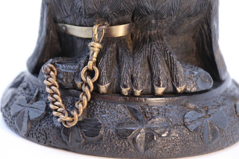 A hand-carved dark oak inkstand crafted in the likeness of an owl with glass eyes and a brass tether, resting on a carved base with shamrock details. View XXIII