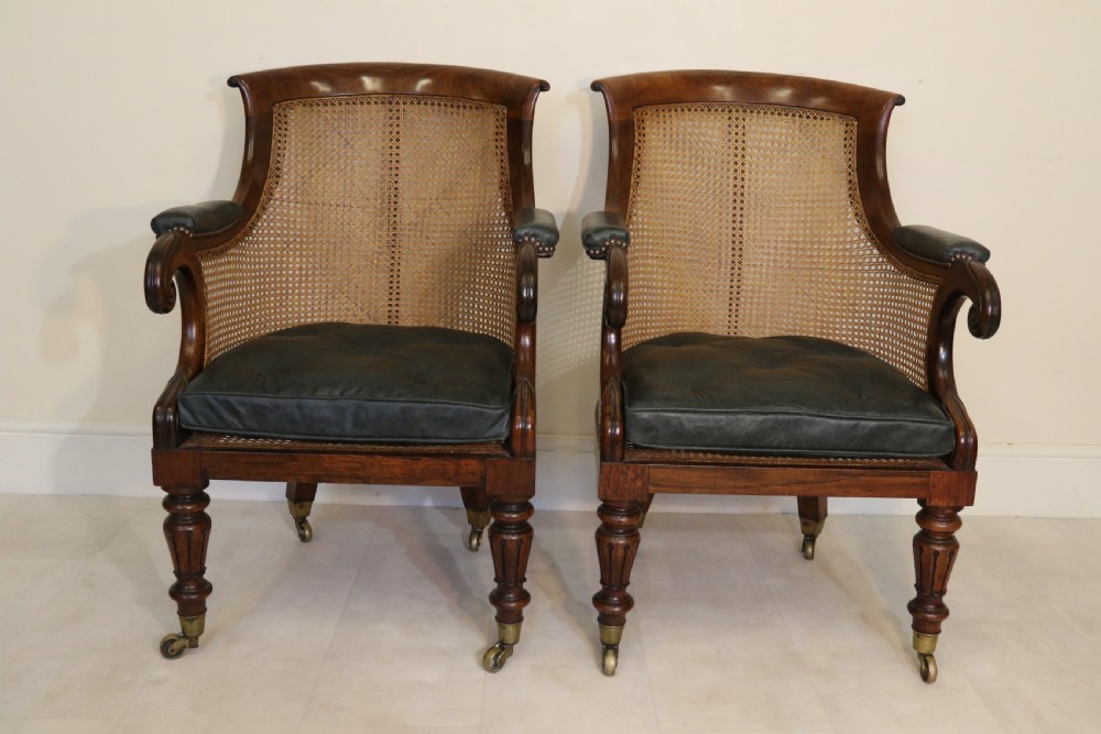 A pair of Regency rosewood bergere library armchairs with hand-woven cane panels, deep green leather cushions, scrolled arms, and turned legs on brass castors. View III
