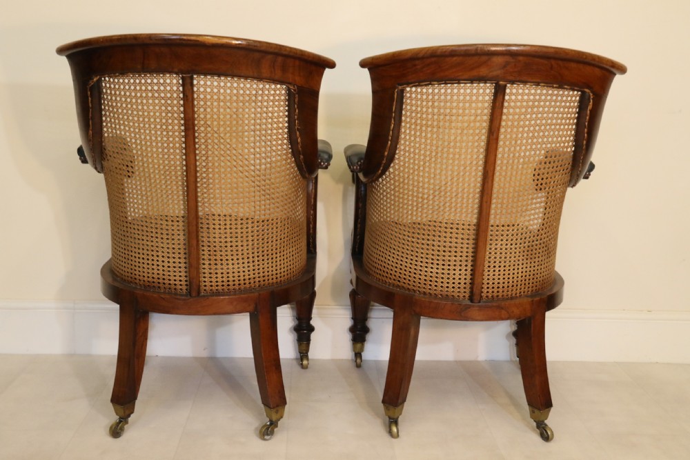 A pair of Regency rosewood bergere library armchairs with hand-woven cane panels, deep green leather cushions, scrolled arms, and turned legs on brass castors. View IV
