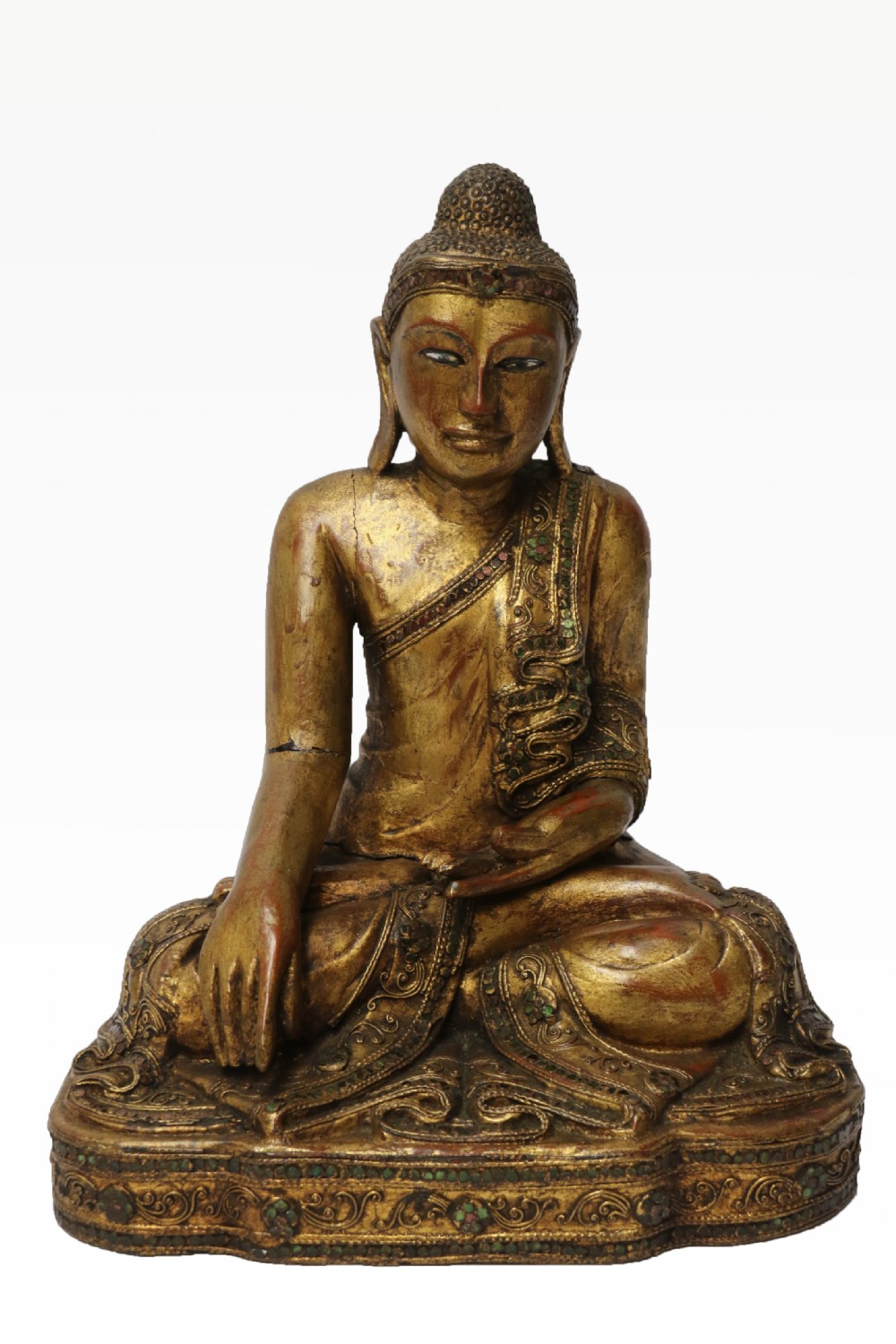 A carved wood Buddha figure in a seated posture decorated in gold gilding with ornamental glass inlay.
