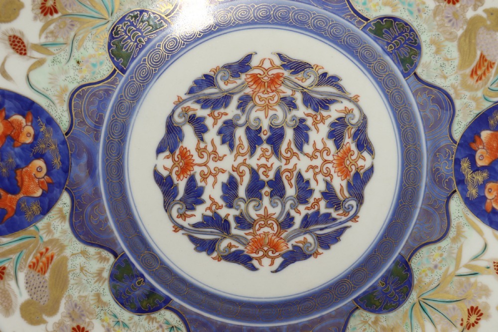 A circular hand-painted Japanese Imari porcelain charger featuring cobalt blue, iron red, and gilt decorative panels depicting birds, goldfish, and botanical motifs. View II