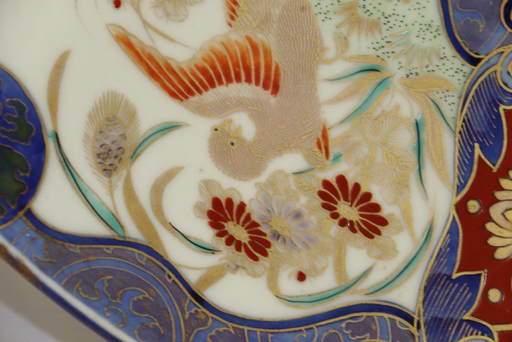 A circular hand-painted Japanese Imari porcelain charger featuring cobalt blue, iron red, and gilt decorative panels depicting birds, goldfish, and botanical motifs. View V