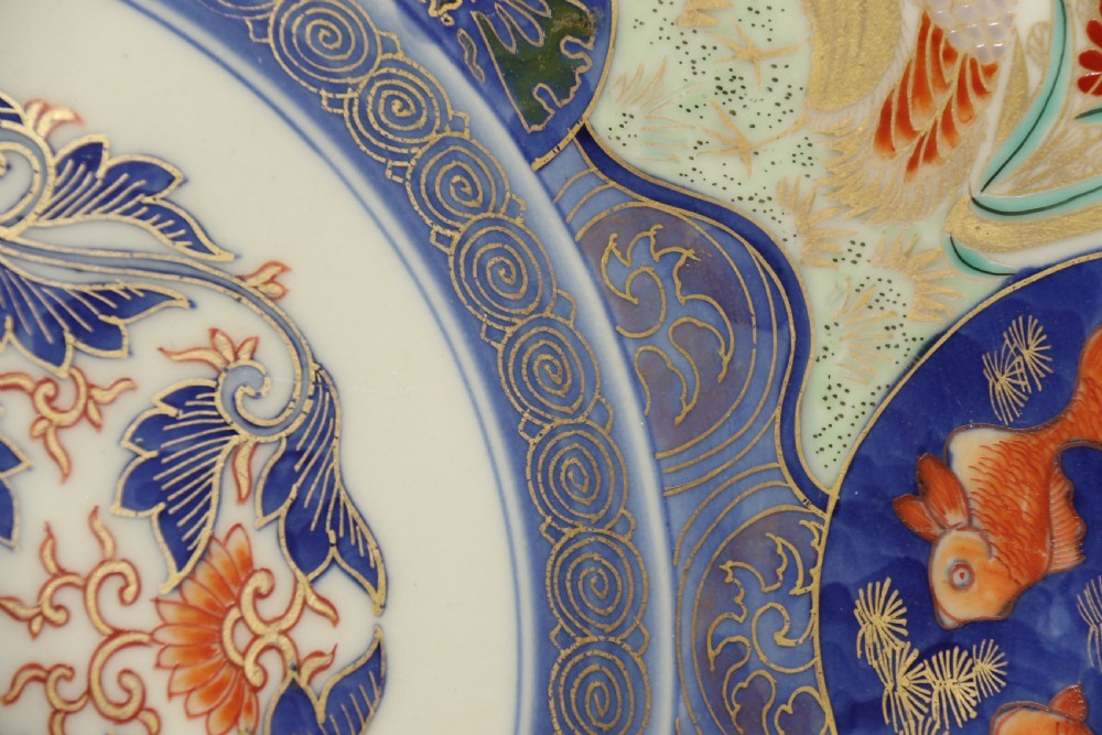 A circular hand-painted Japanese Imari porcelain charger featuring cobalt blue, iron red, and gilt decorative panels depicting birds, goldfish, and botanical motifs. View VI