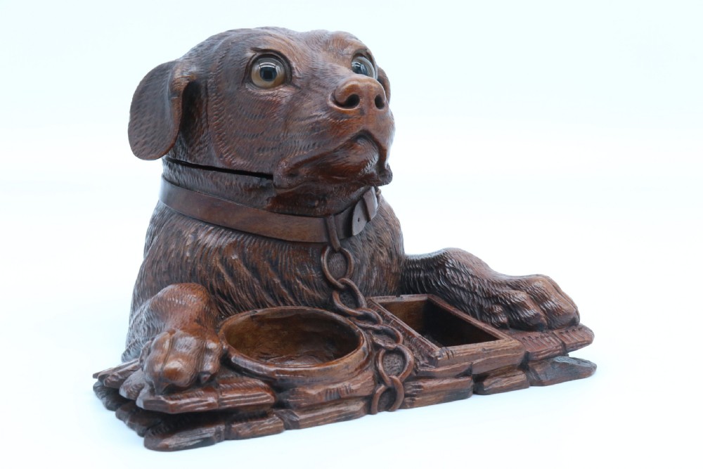 A 19th-century carved wooden tobacco box formed as a dog head with glass eyes and a hinged lid, set on a base with carved trays. View II