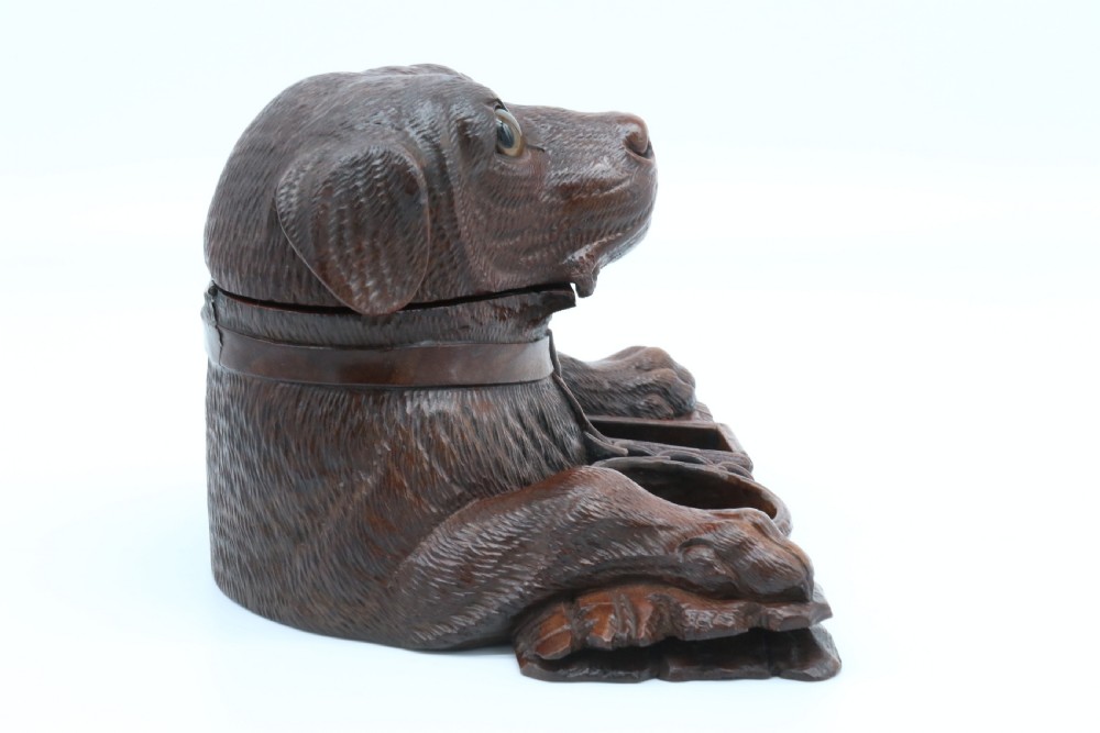 A 19th-century carved wooden tobacco box formed as a dog head with glass eyes and a hinged lid, set on a base with carved trays. View IV
