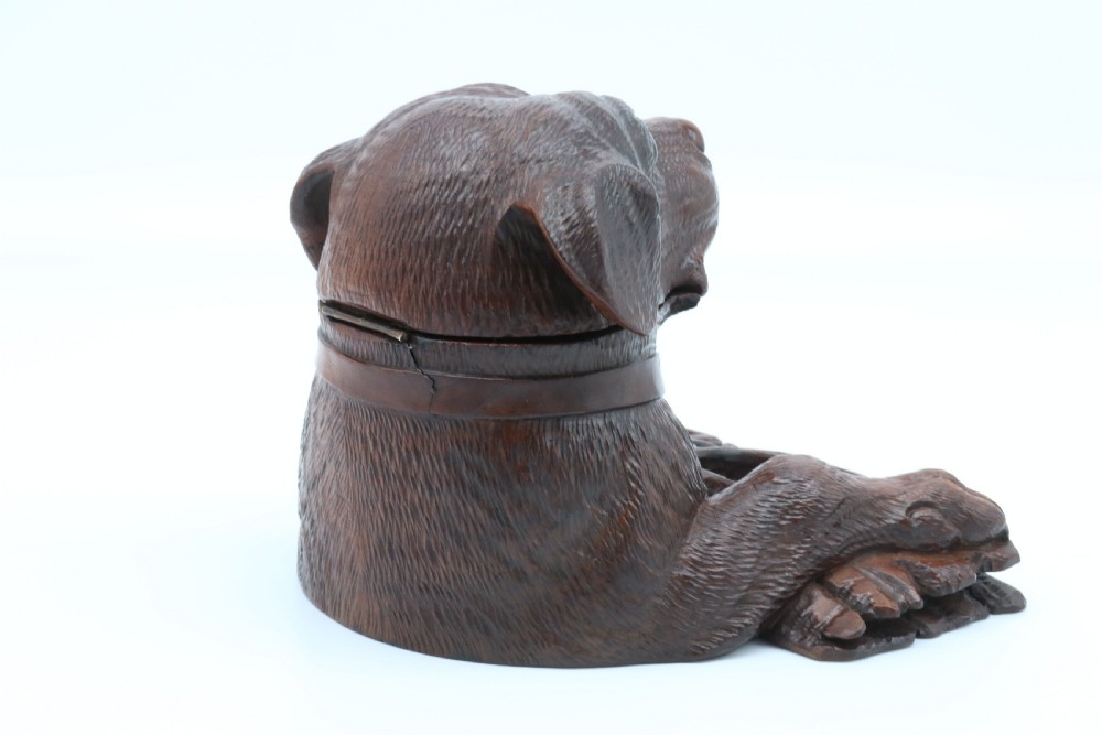 A 19th-century carved wooden tobacco box formed as a dog head with glass eyes and a hinged lid, set on a base with carved trays. View V