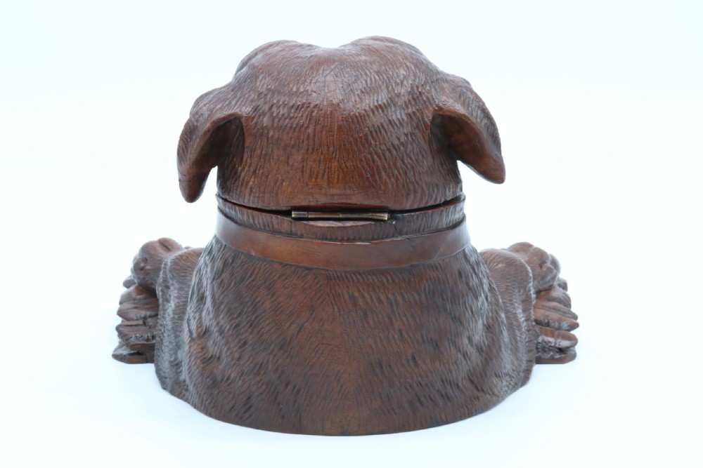 A 19th-century carved wooden tobacco box formed as a dog head with glass eyes and a hinged lid, set on a base with carved trays. View VI