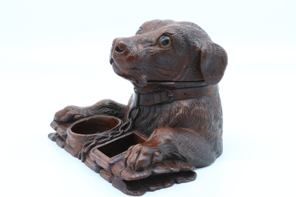 A 19th-century carved wooden tobacco box formed as a dog head with glass eyes and a hinged lid, set on a base with carved trays. View IX