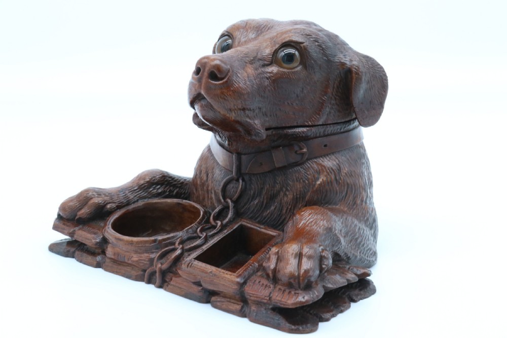 A 19th-century carved wooden tobacco box formed as a dog head with glass eyes and a hinged lid, set on a base with carved trays. View X