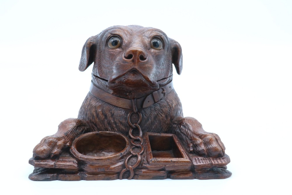 A 19th-century carved wooden tobacco box formed as a dog head with glass eyes and a hinged lid, set on a base with carved trays. View XI