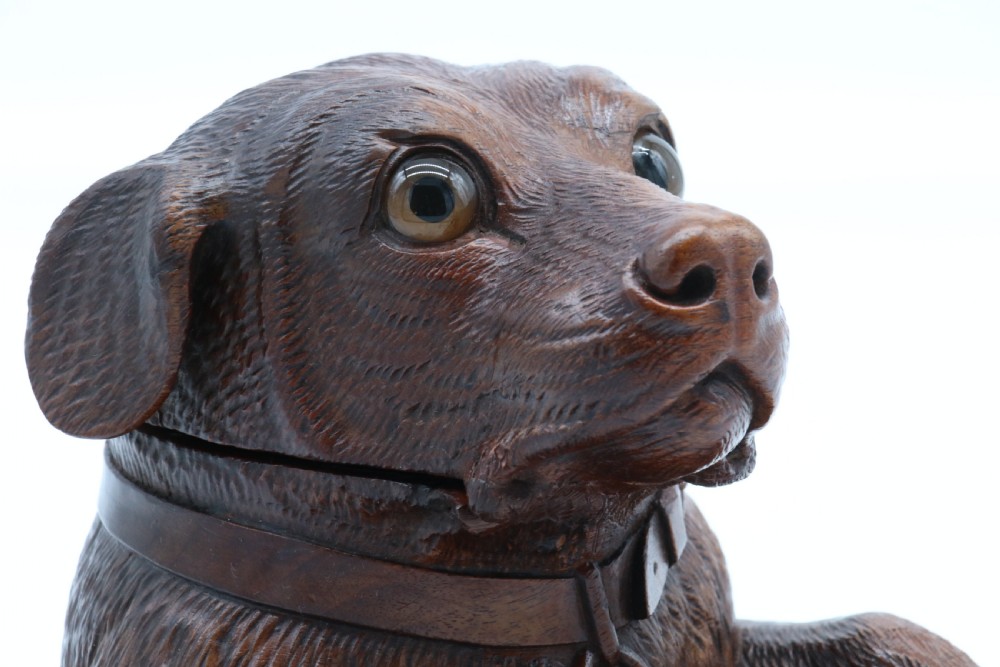 A 19th-century carved wooden tobacco box formed as a dog head with glass eyes and a hinged lid, set on a base with carved trays. View XII