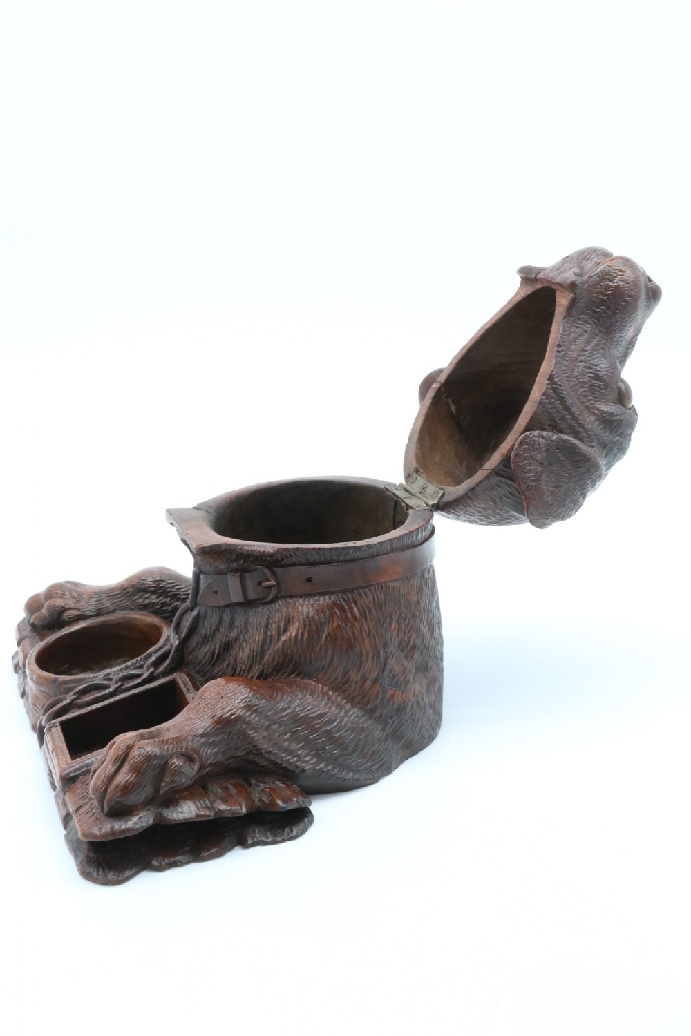 A 19th-century carved wooden tobacco box formed as a dog head with glass eyes and a hinged lid, set on a base with carved trays. View XVII