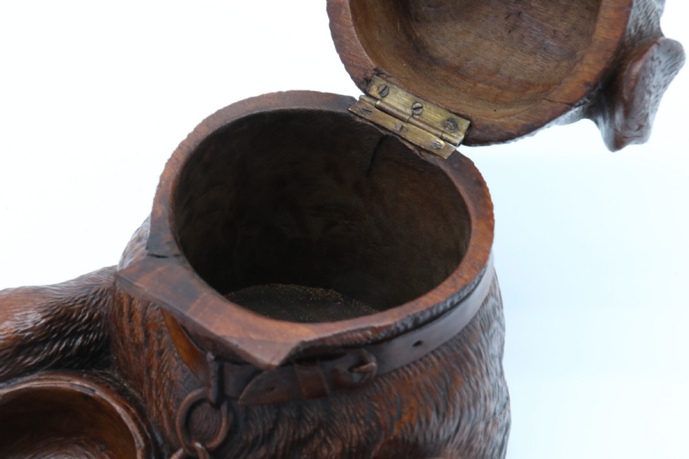 A 19th-century carved wooden tobacco box formed as a dog head with glass eyes and a hinged lid, set on a base with carved trays. View XIX