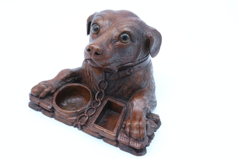 A 19th-century carved wooden tobacco box formed as a dog head with glass eyes and a hinged lid, set on a base with carved trays. View XXI