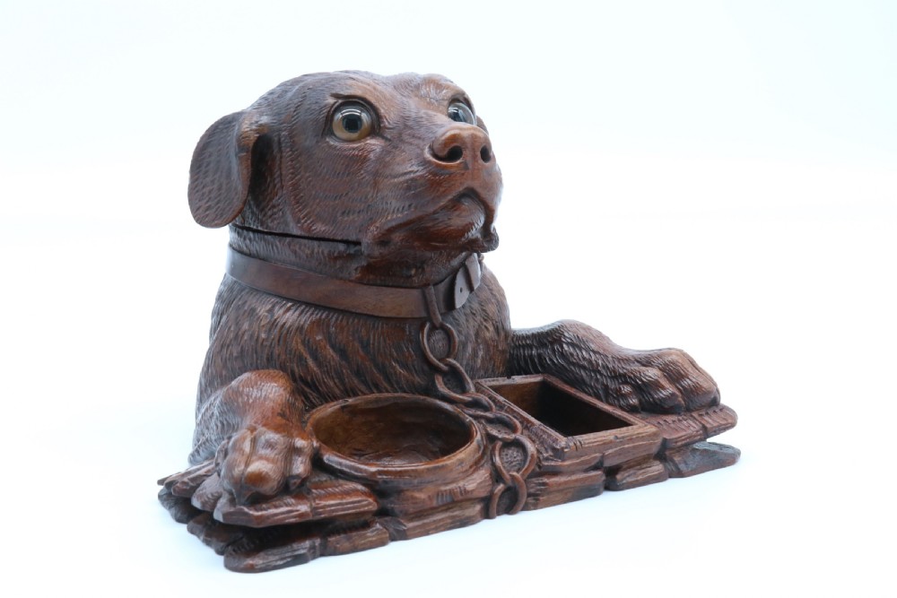 A 19th-century carved wooden tobacco box formed as a dog head with glass eyes and a hinged lid, set on a base with carved trays. View XXIV