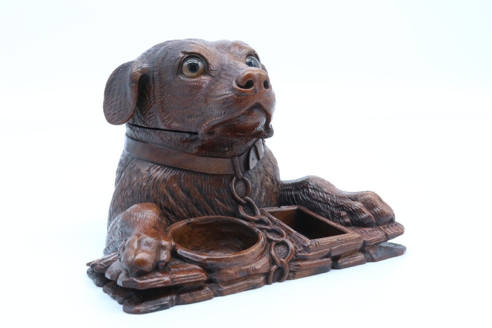 A 19th-century carved wooden tobacco box formed as a dog head with glass eyes and a hinged lid, set on a base with carved trays. View XXV