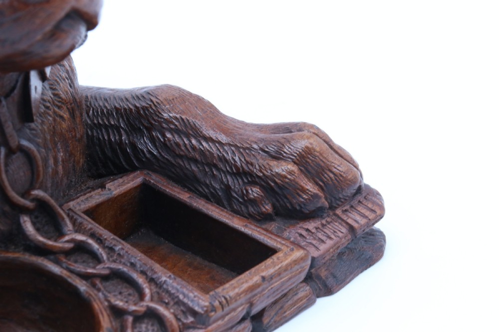 A 19th-century carved wooden tobacco box formed as a dog head with glass eyes and a hinged lid, set on a base with carved trays. View XXVII