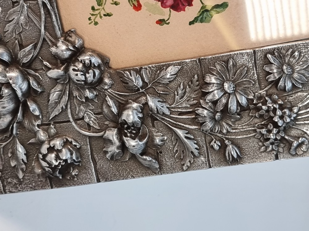 An Aesthetic Movement pewter picture frame featuring embossed insect and floral relief decoration around a central floral watercolour illustration. View VI