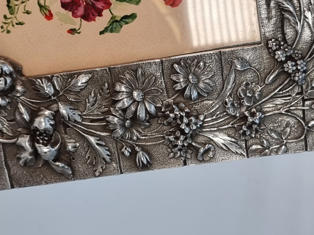 An Aesthetic Movement pewter picture frame featuring embossed insect and floral relief decoration around a central floral watercolour illustration. View VII