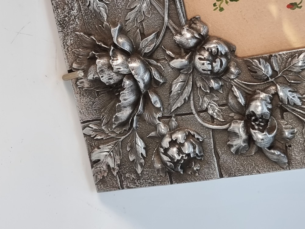 An Aesthetic Movement pewter picture frame featuring embossed insect and floral relief decoration around a central floral watercolour illustration. View XIV