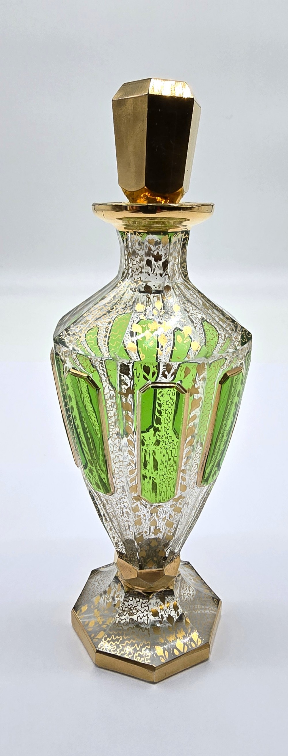 A Bohemian glass perfume bottle with green overlay and gilt decoration.