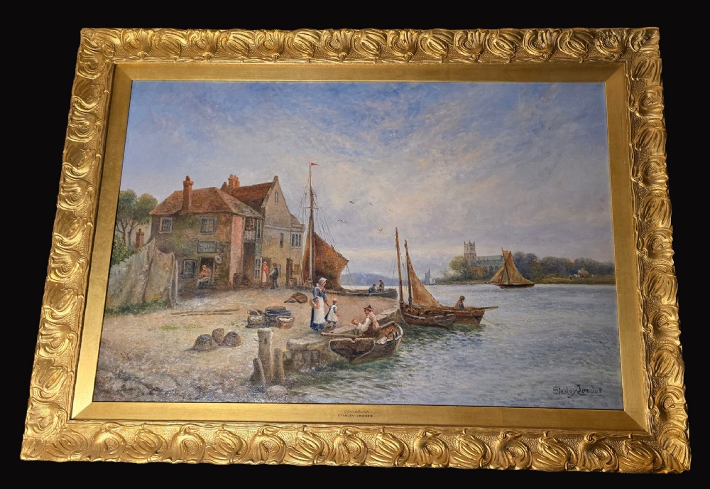 An oil painting depicting a harbour scene with sailboats and buildings, encased in a carved gold gilt frame.