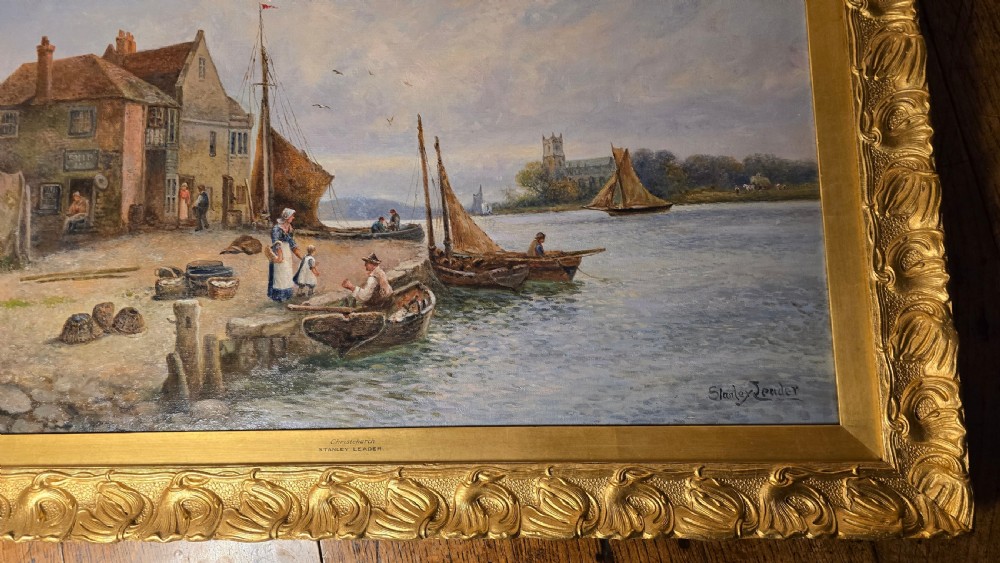 An oil painting depicting a harbour scene with sailboats and buildings, encased in a carved gold gilt frame. View II
