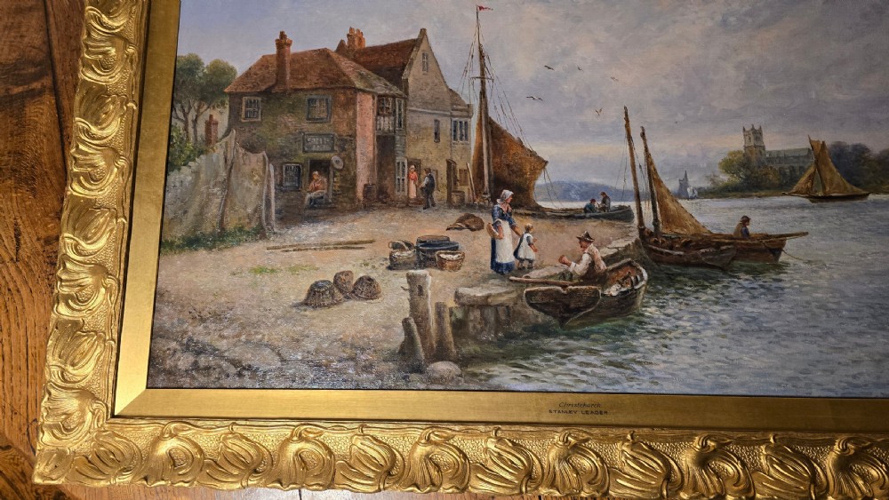 An oil painting depicting a harbour scene with sailboats and buildings, encased in a carved gold gilt frame. View III
