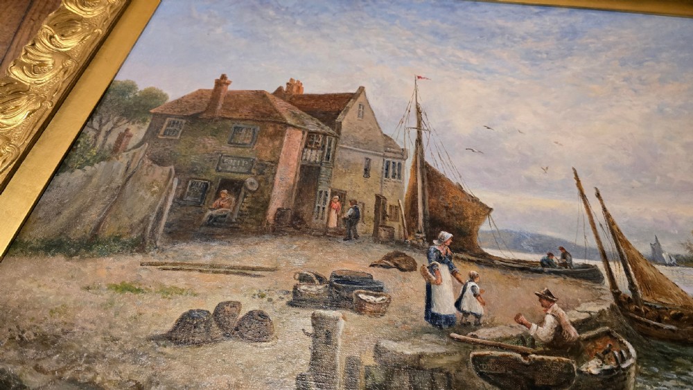 An oil painting depicting a harbour scene with sailboats and buildings, encased in a carved gold gilt frame. View X