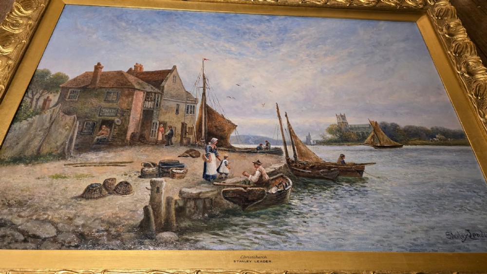 An oil painting depicting a harbour scene with sailboats and buildings, encased in a carved gold gilt frame. View XI