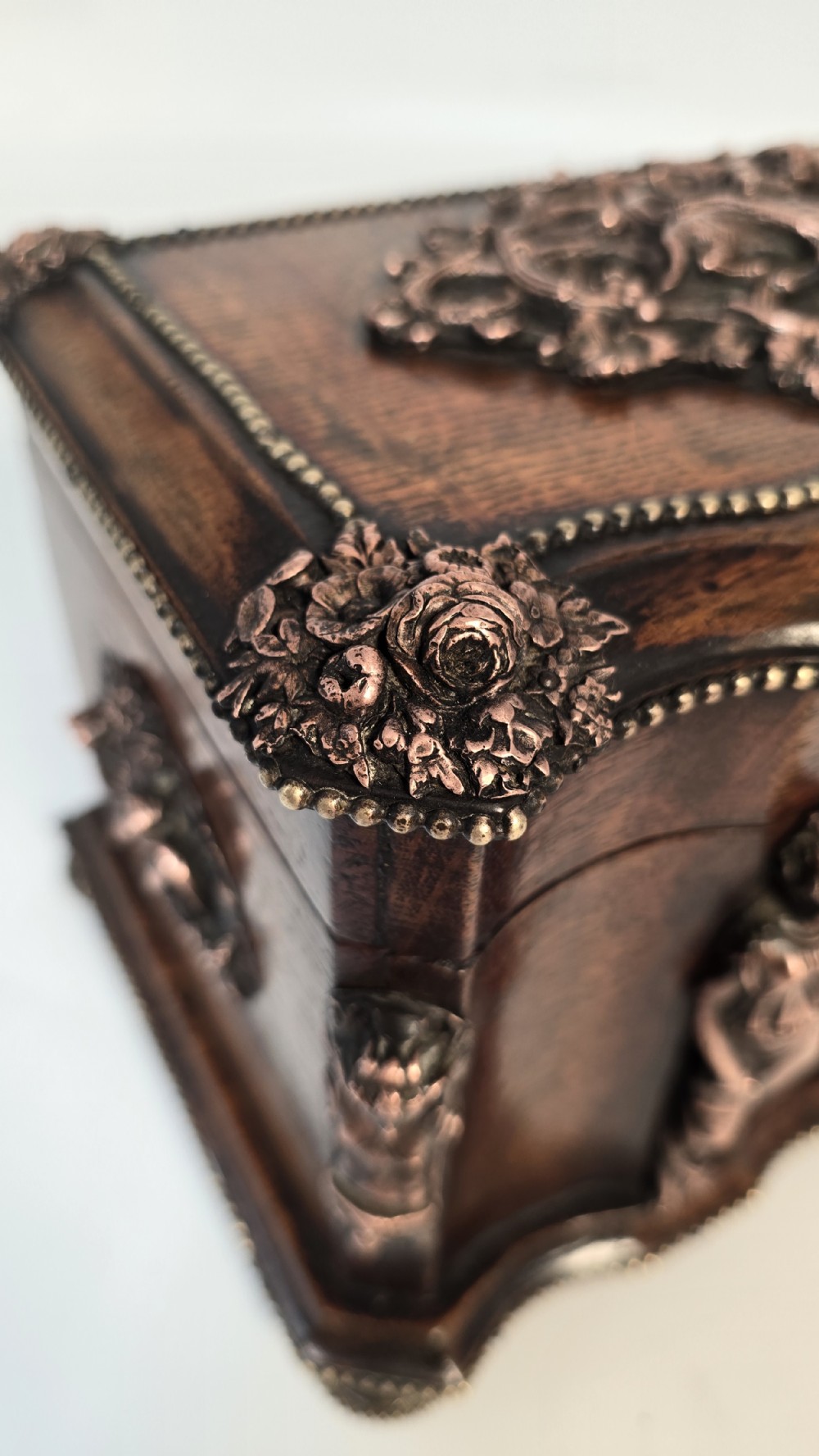 A dark carved oak tea caddy featuring copper relief caryatids, a central lock plate, and a decorative figural lid crest. View XII