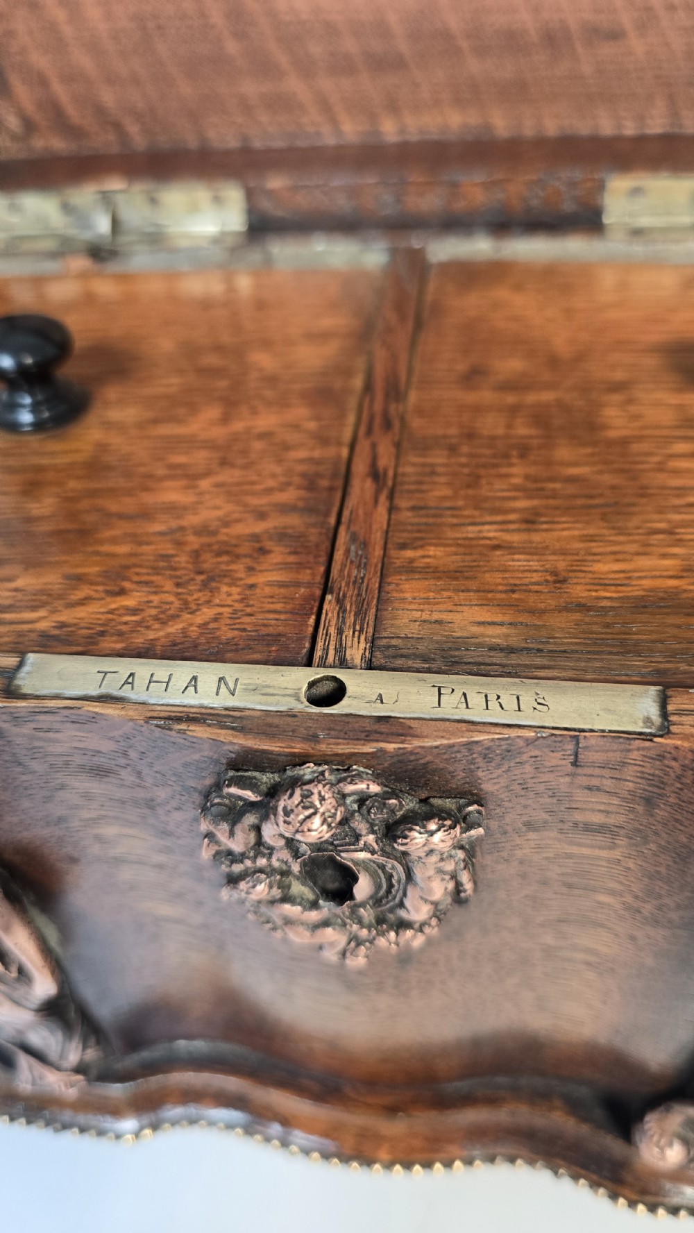 A dark carved oak tea caddy featuring copper relief caryatids, a central lock plate, and a decorative figural lid crest. View XIX