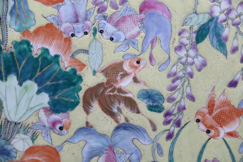 A circular framed Chinese porcelain plaque featuring vibrant hand-painted goldfish and lotus flowers on a yellow background enclosed in a carved dark frame. View VI