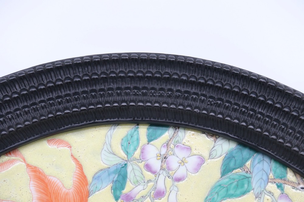 A circular framed Chinese porcelain plaque featuring vibrant hand-painted goldfish and lotus flowers on a yellow background enclosed in a carved dark frame. View XI